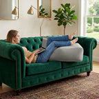 Close-up of a hand pressing on a partially inflated leg elevation pillow, demonstrating adjustable firmness
