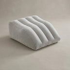 Close-up of a hand pressing on a partially inflated leg elevation pillow, demonstrating adjustable firmness
