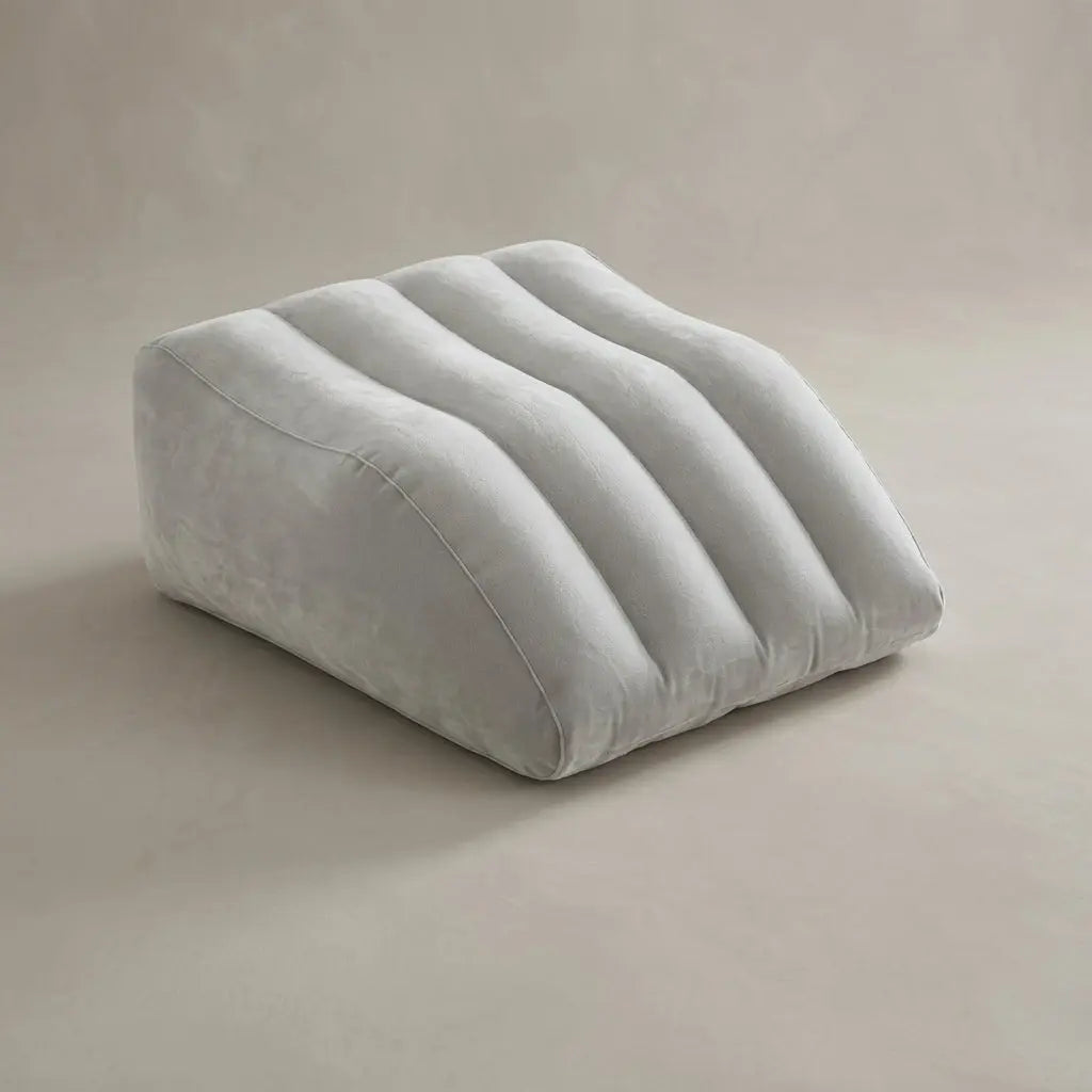 Close-up of a hand pressing on a partially inflated leg elevation pillow, demonstrating adjustable firmness